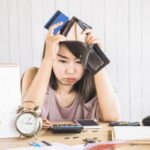 depressed Asian woman having problem with debt hand holding empty wallet and credit card